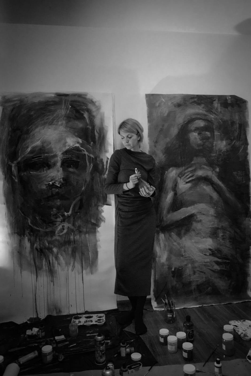 The artist standing between two works in progress.