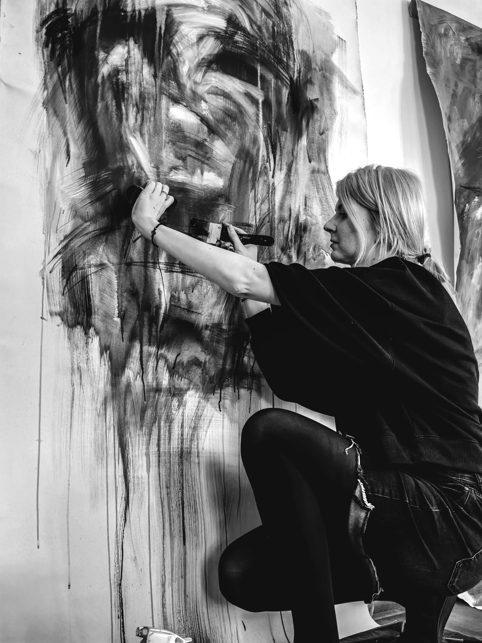 The artist making marks on a large figurative painting.