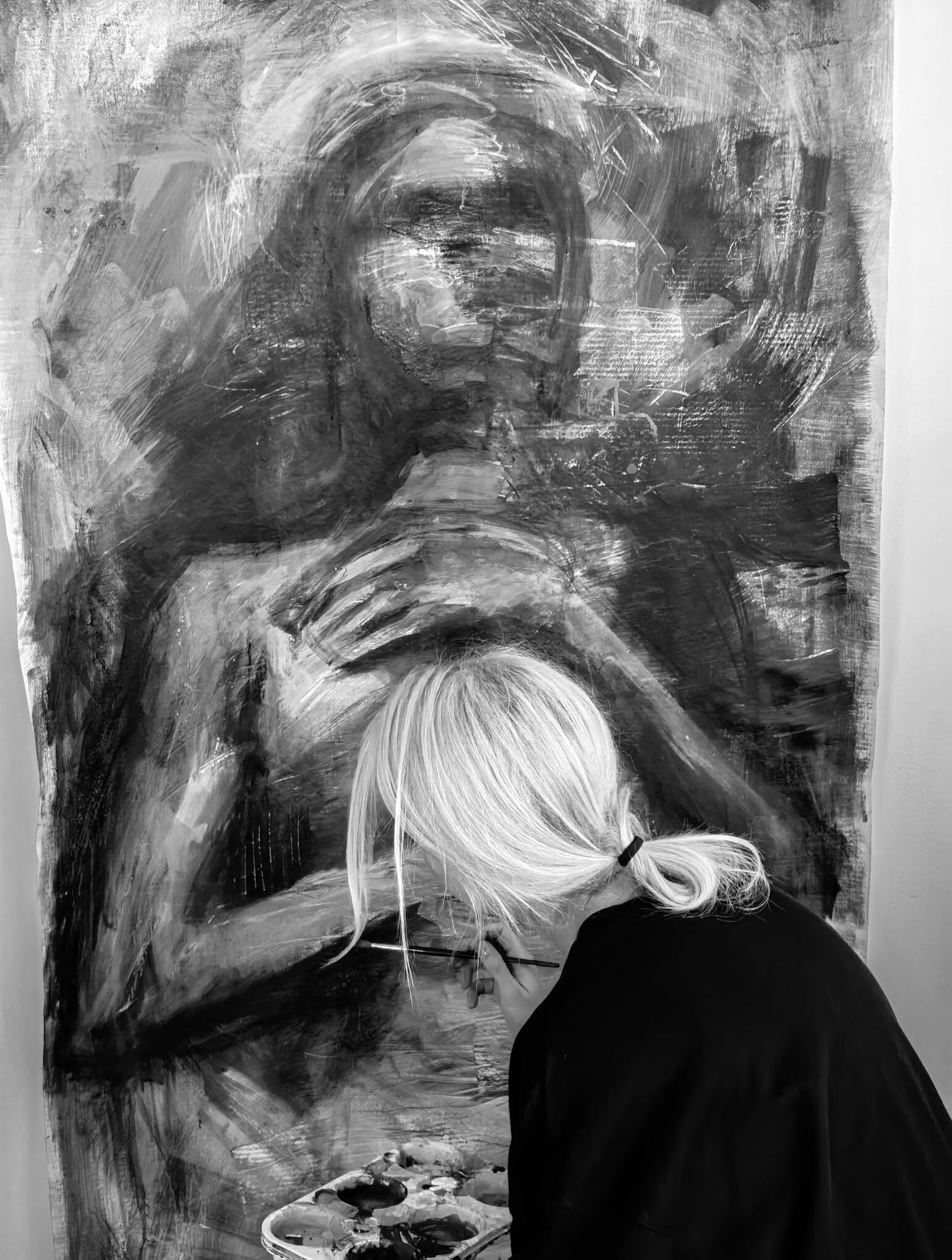 The artist seen from behind, working on a figurative composition.