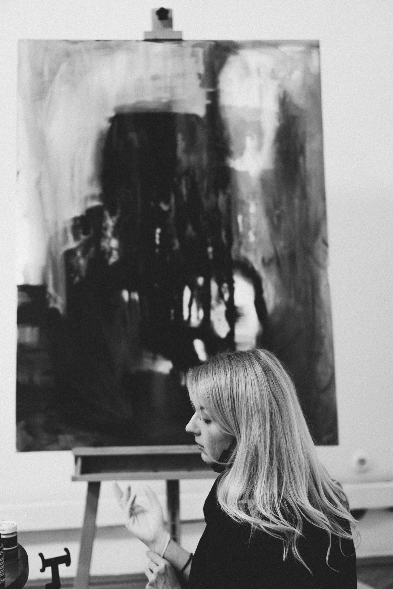 Black-and-white photograph of Anita Frâncu in profile, in front of the painting on the easel.