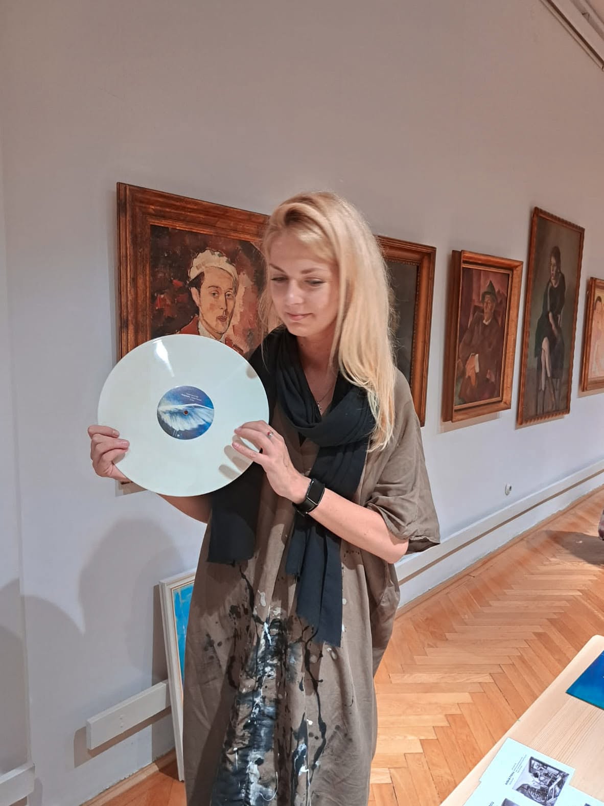 Anita Frâncu holding a light-coloured vinyl record in the museum gallery.